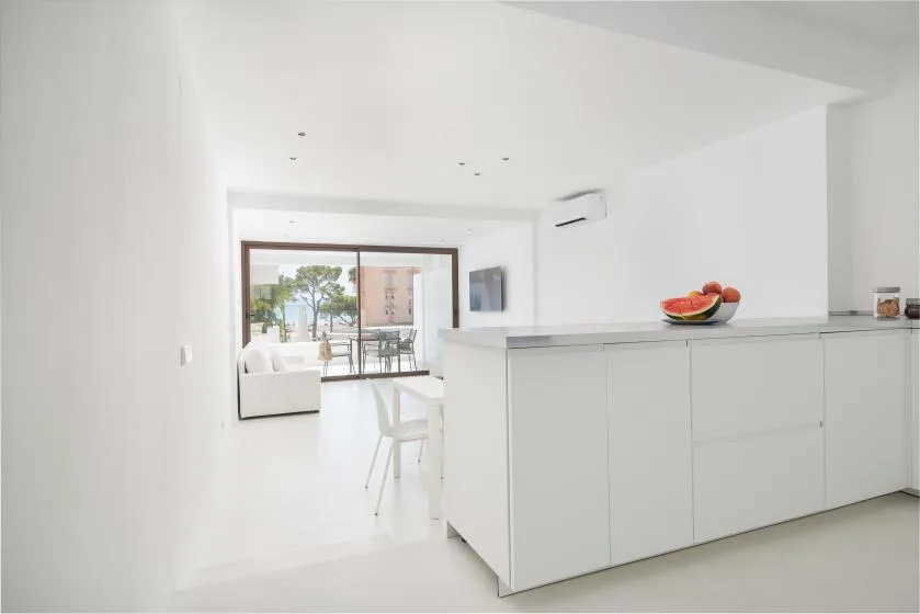 A bright open-plan kitchen with a white island and seating by the windows.
