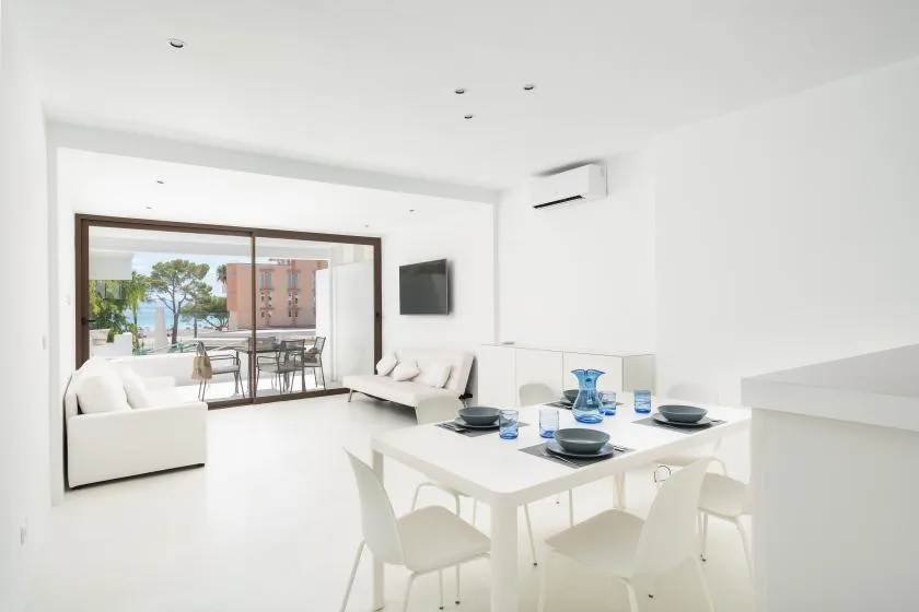 A bright living and dining area opens onto a balcony through wide sliding glass doors.