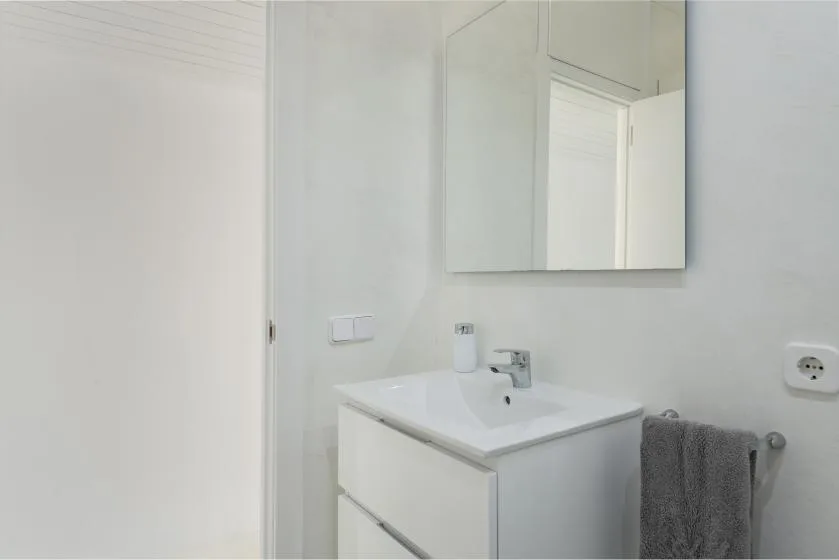 A bright bathroom vanity with a sink, mirror, and gray towel.