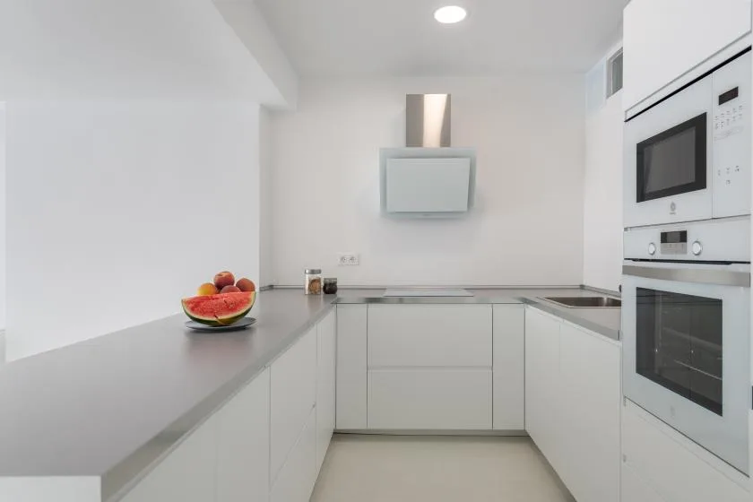 A bright white kitchen with a countertop and built-in appliances.