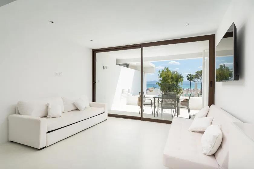 Una sala luminosa se abre a un patio con asientos al aire libre y vistas al mar.