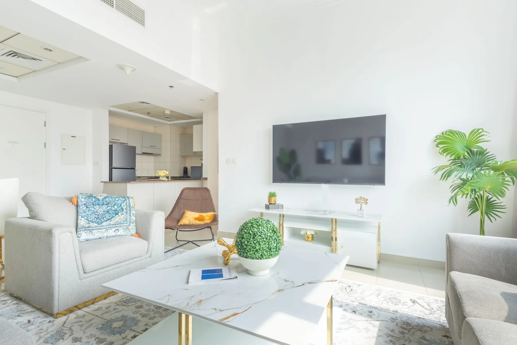 Una sala luminosa con asientos, una mesa de centro y un televisor montado en la pared.