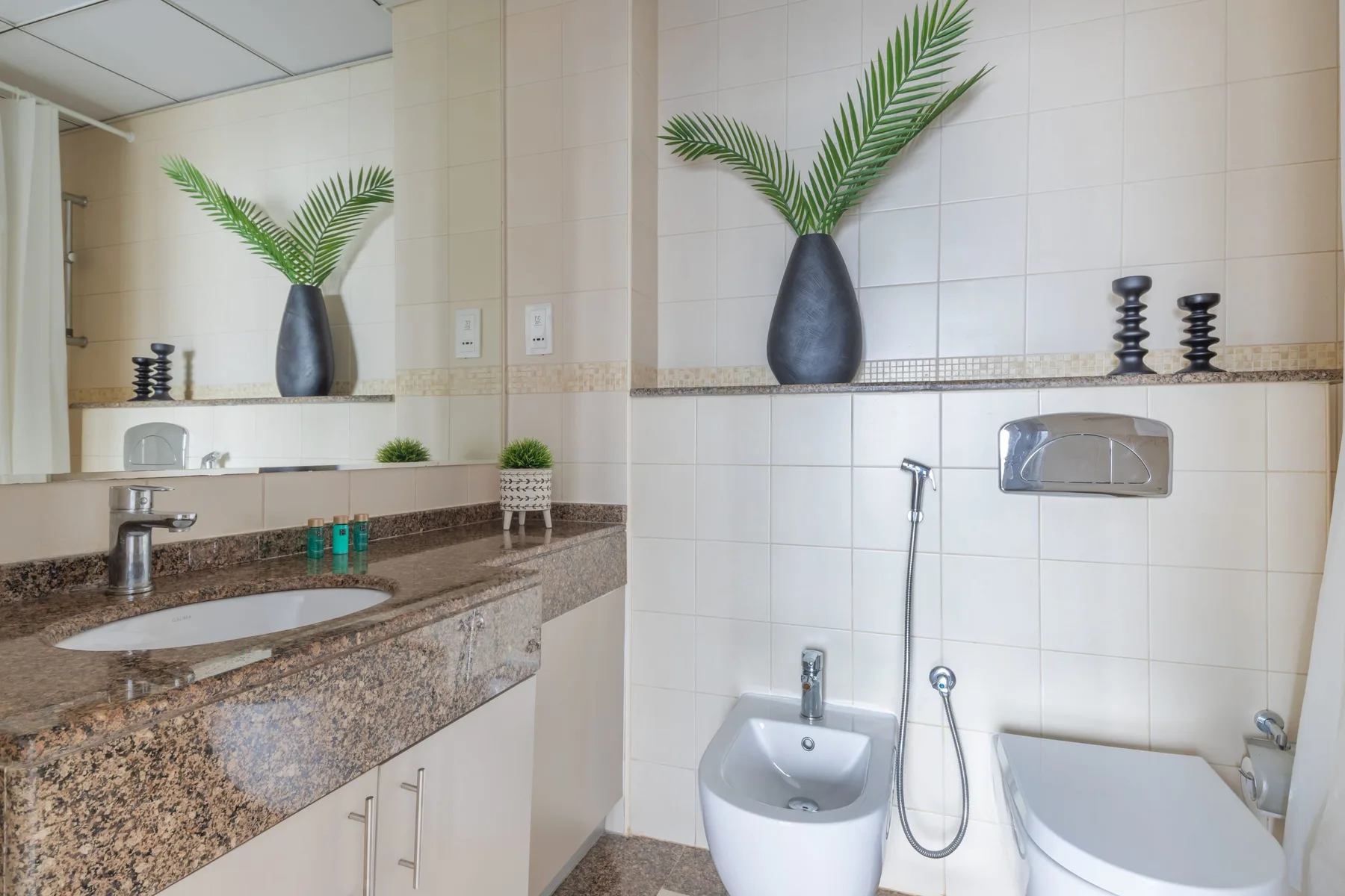 Un baño alicatado con lavabo, inodoro suspendido y encimera.