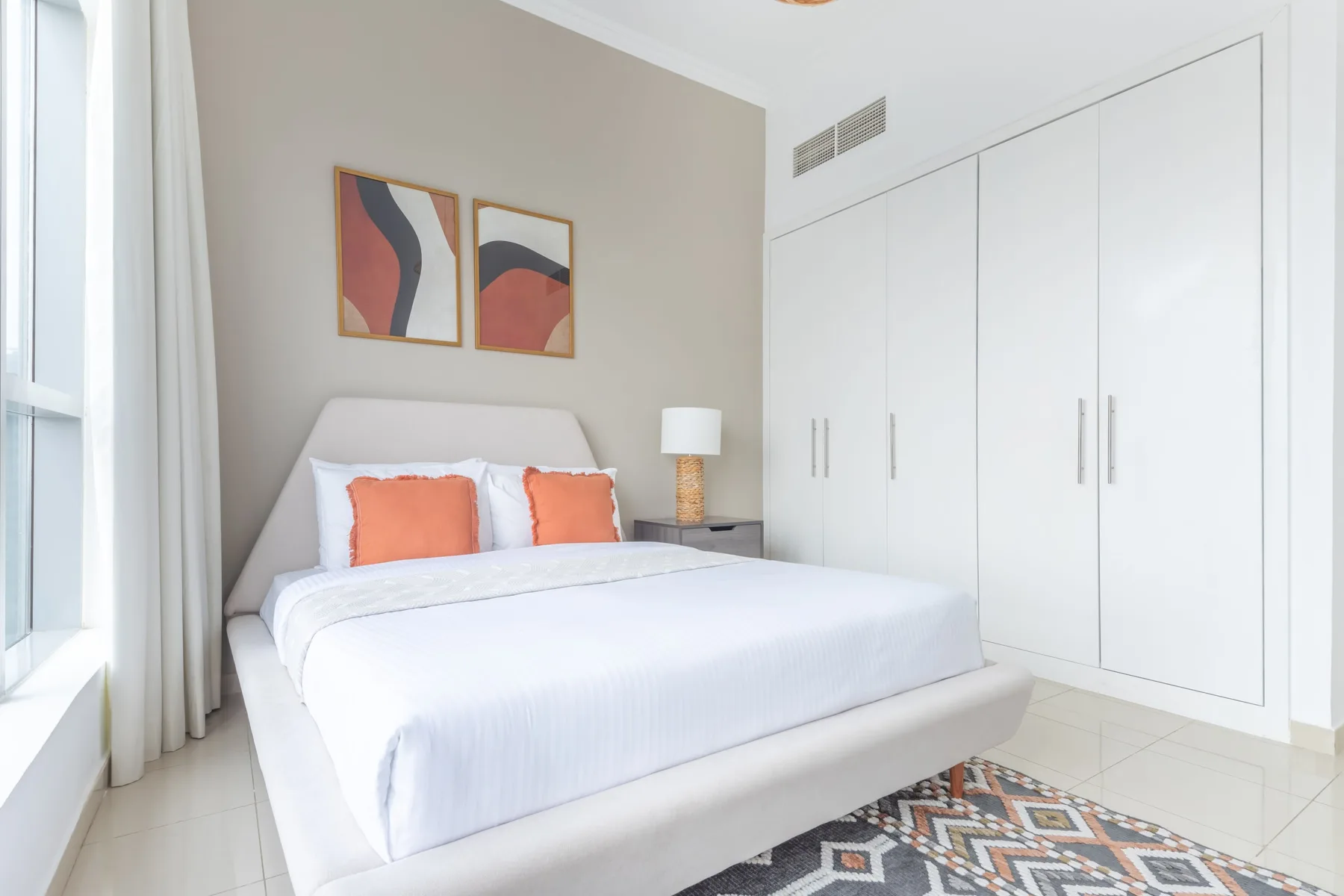 Un dormitorio luminoso con una cama bien tendida y armarios blancos empotrados.