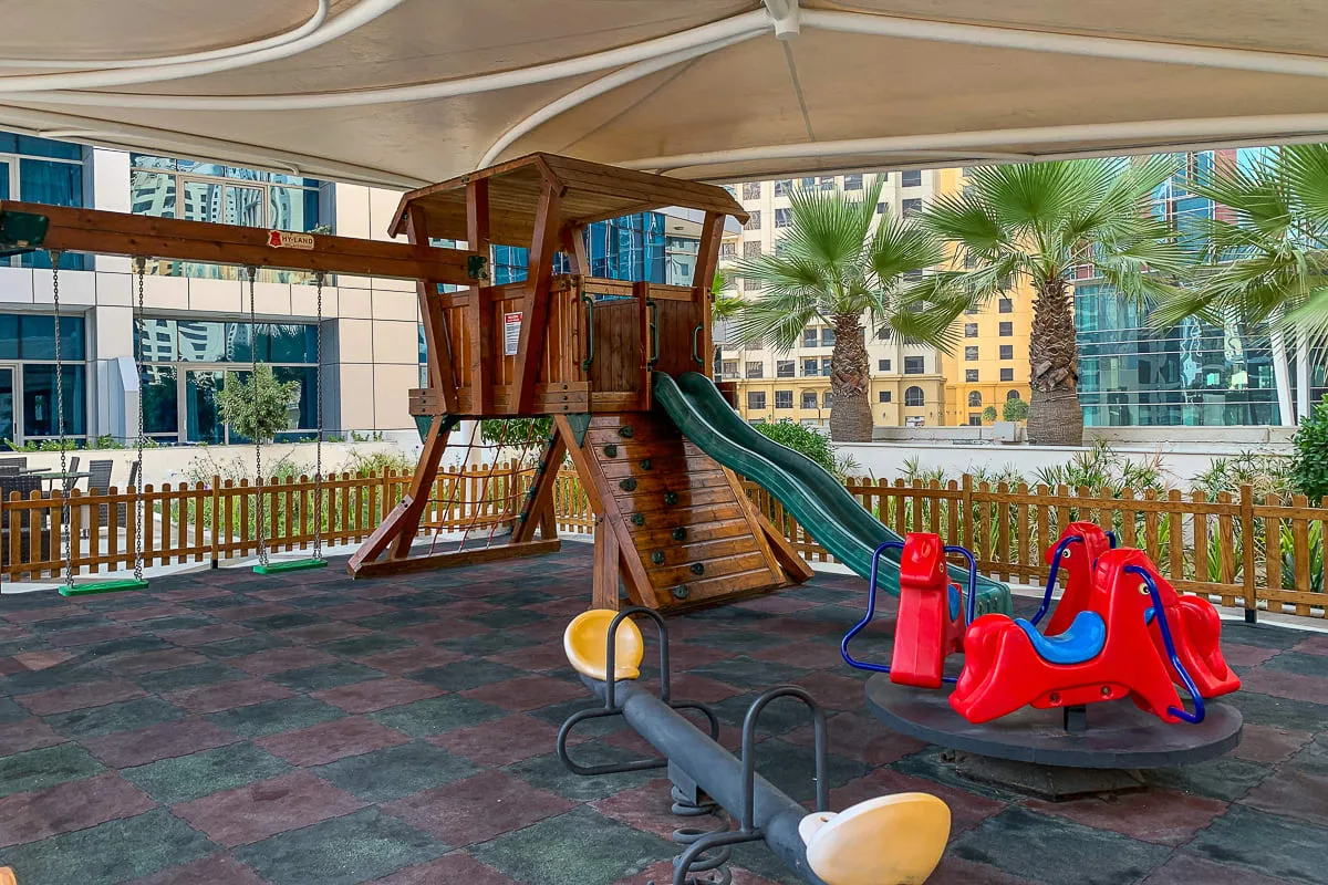 Un parque infantil al aire libre con una estructura de madera y juegos coloridos.