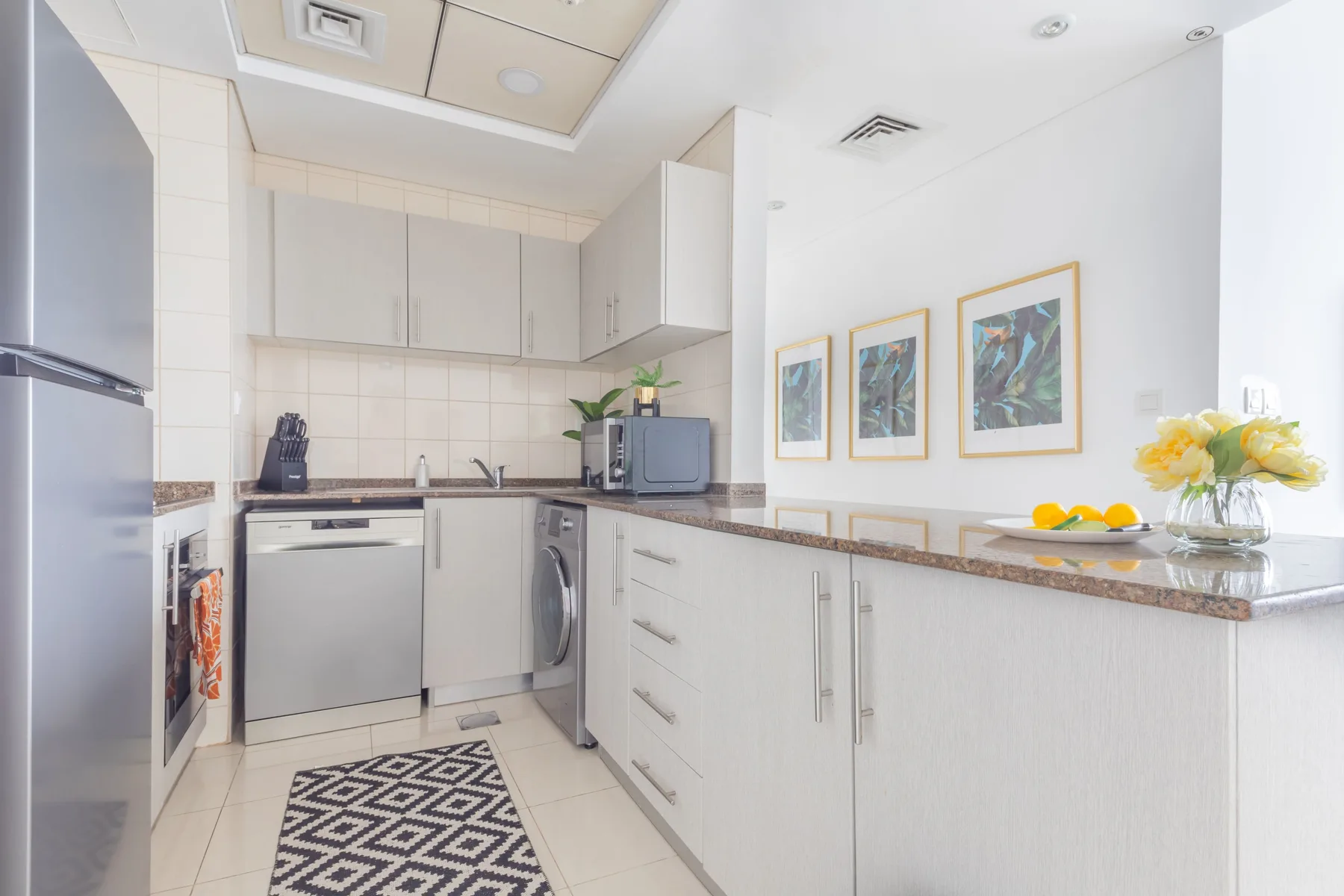 Una cocina luminosa con gabinetes claros, una encimera y electrodomésticos integrados.