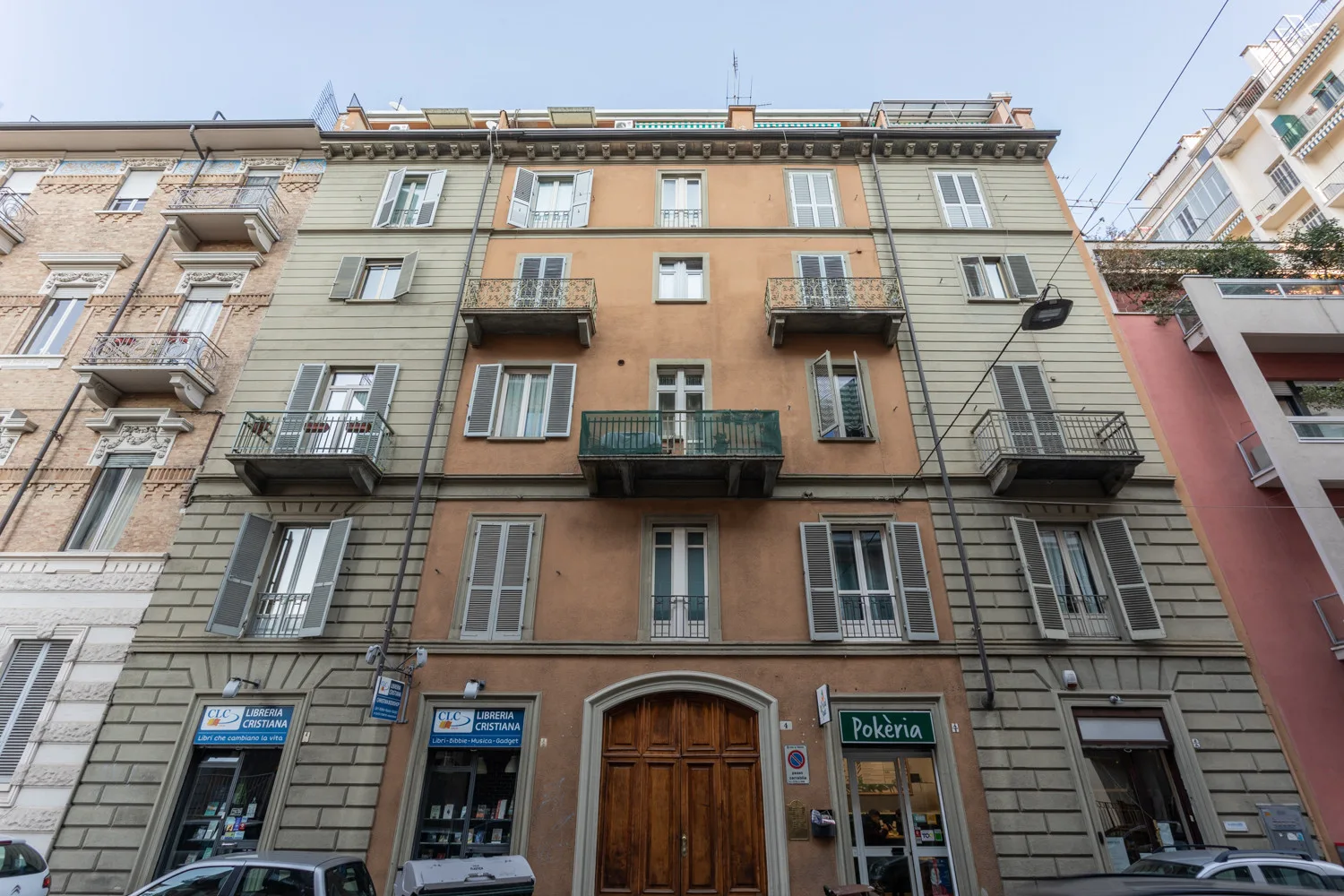 A multistory apartment building with balconies and storefronts at street level.