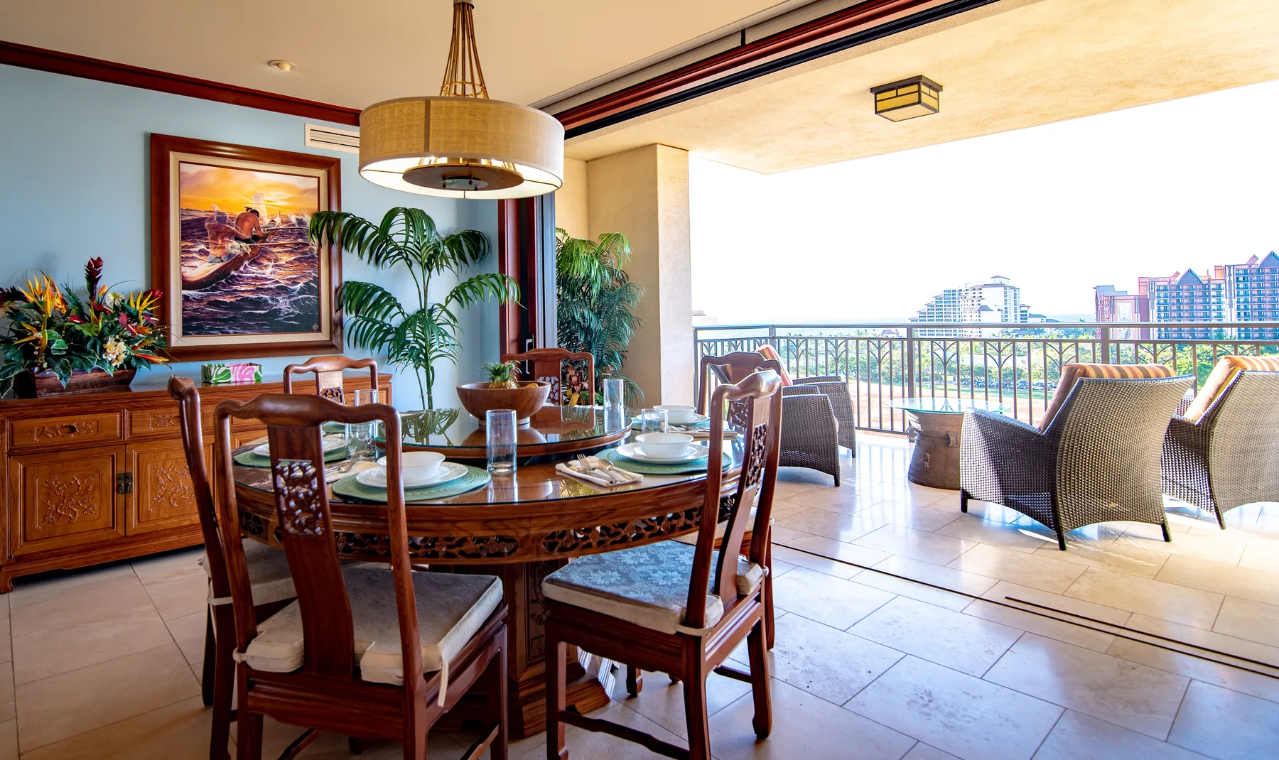 A dining area opens onto a balcony with outdoor seating and a city view.