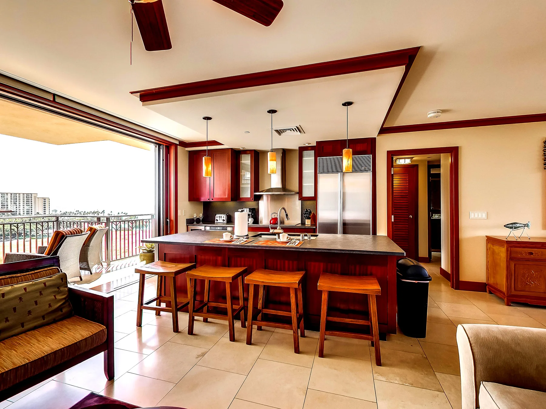 An open kitchen with a breakfast bar and seating opens onto a balcony.