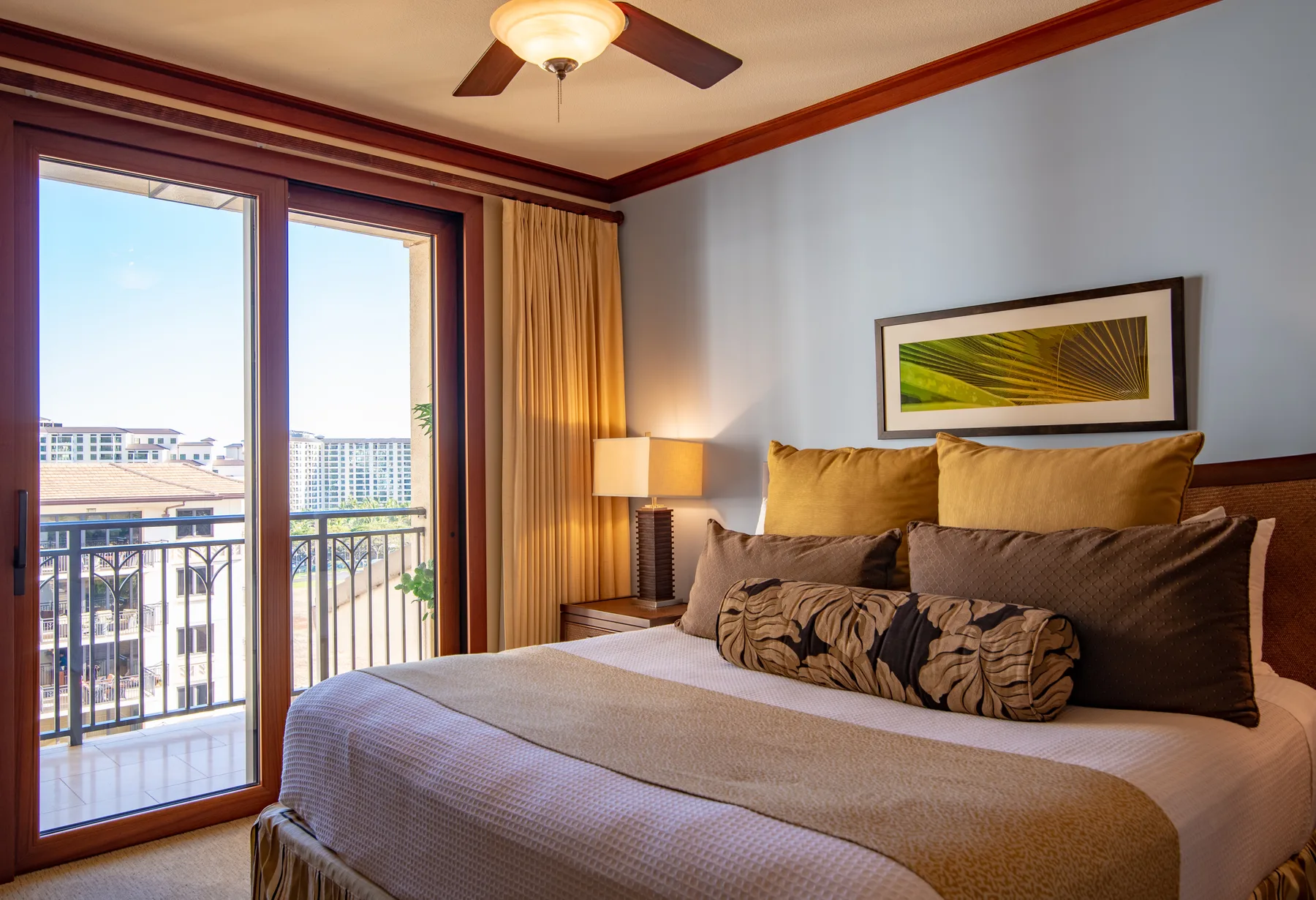 A bedroom with a bed beside tall glass doors opening onto a balcony.