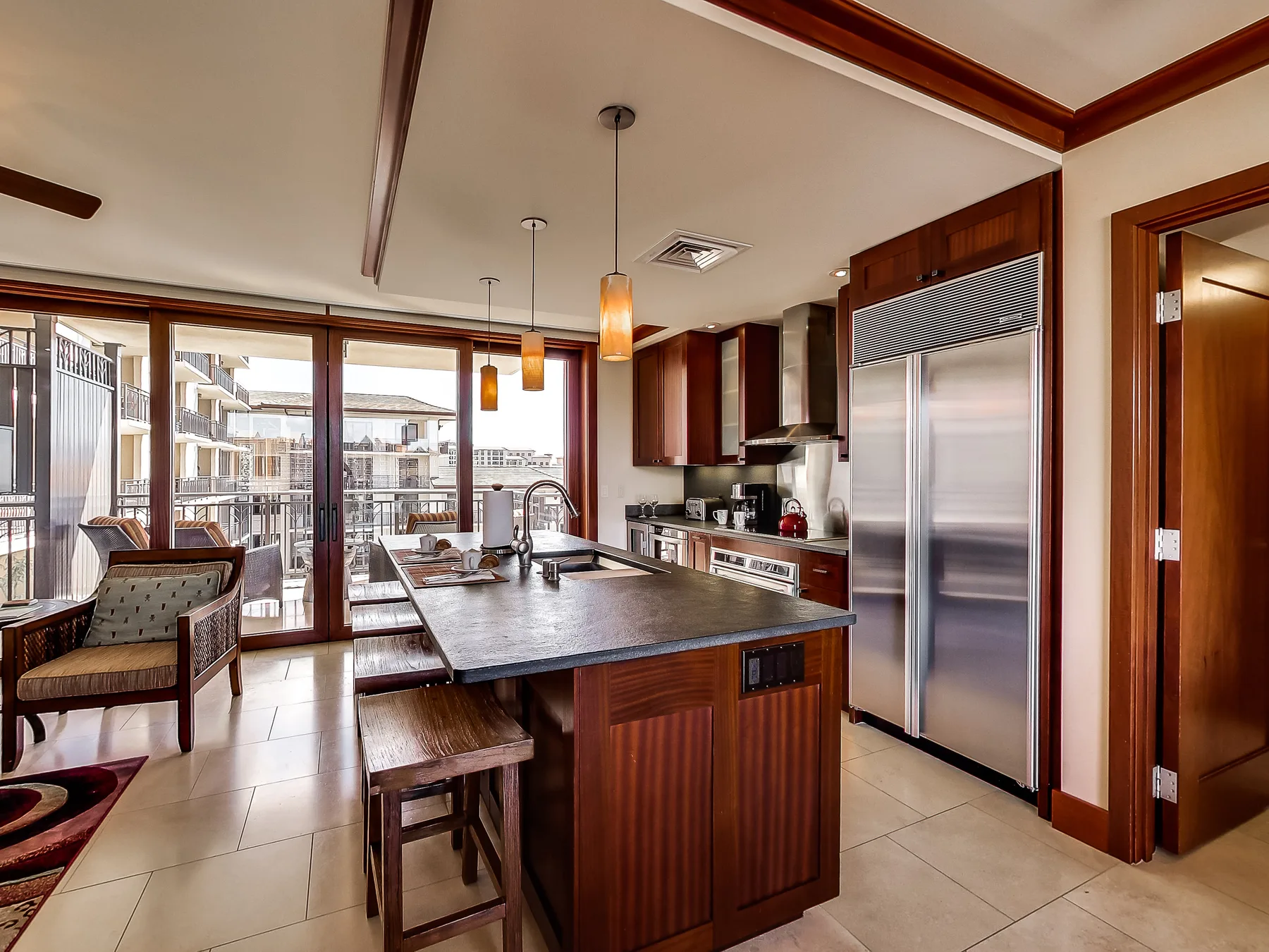 A modern kitchen with a central island and large windows overlooking a balcony.