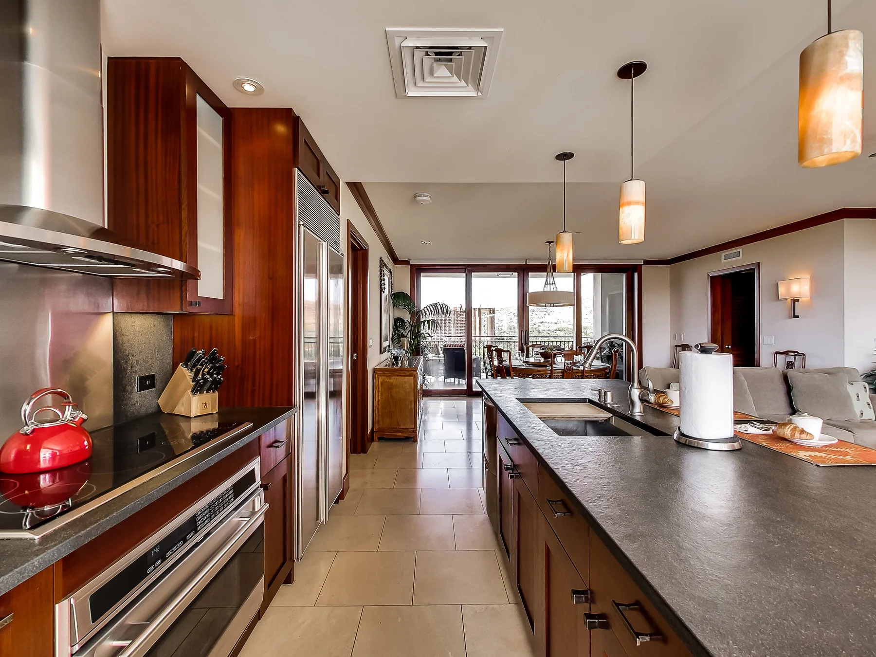 A modern kitchen with a long island and large windows overlooking a dining area.