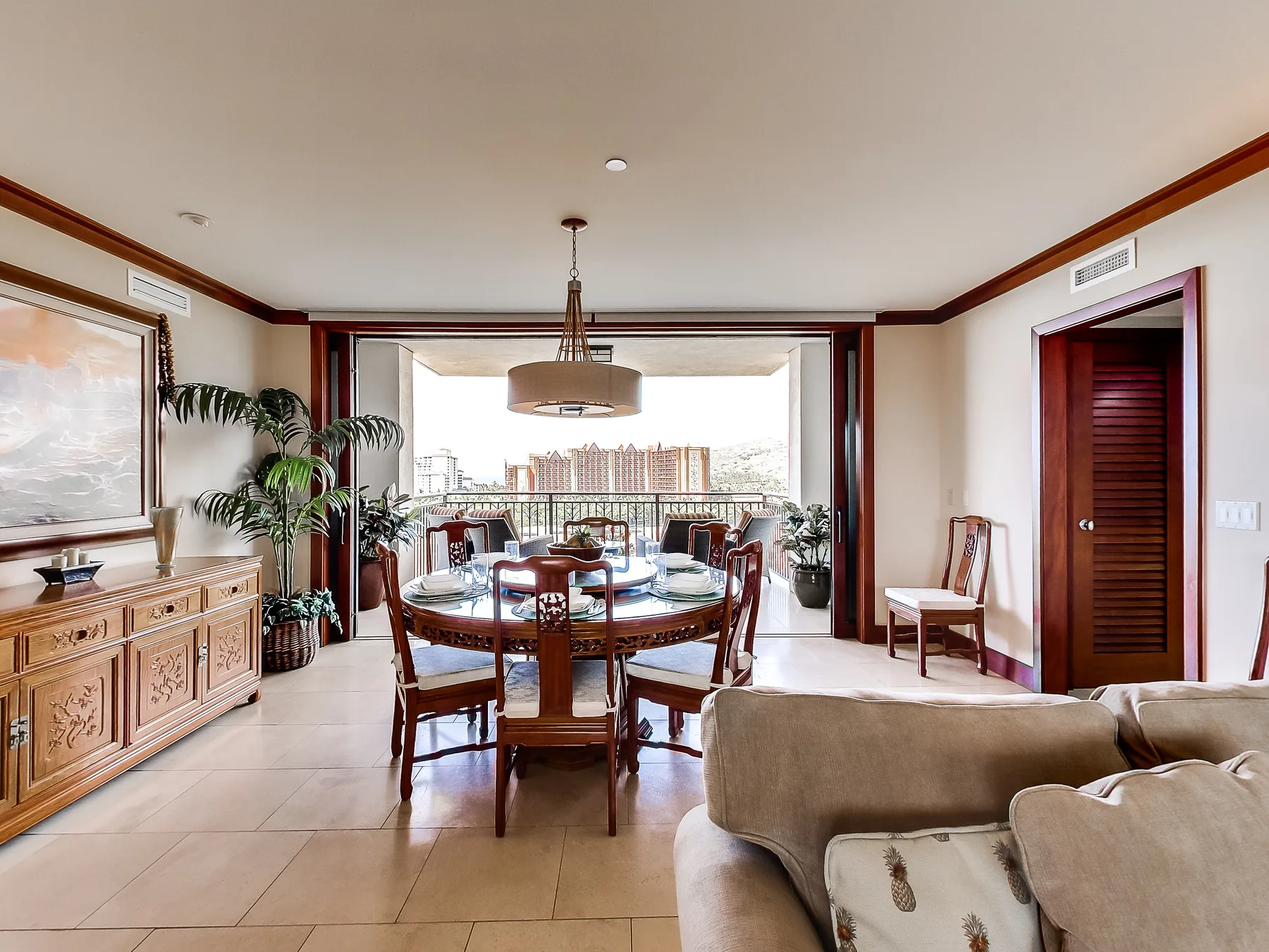A dining area opens onto a balcony, with a table and seating beside the living room.
