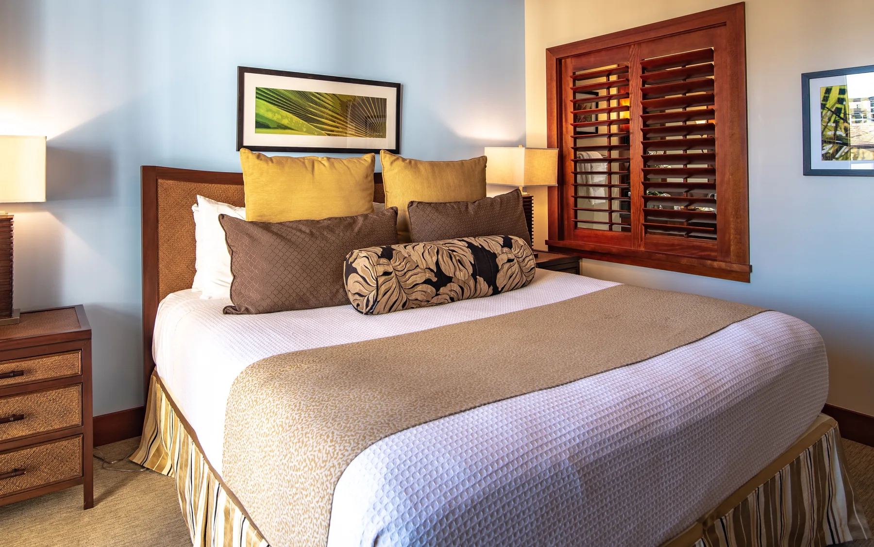 A bedroom with a neatly made bed and wooden shutters.