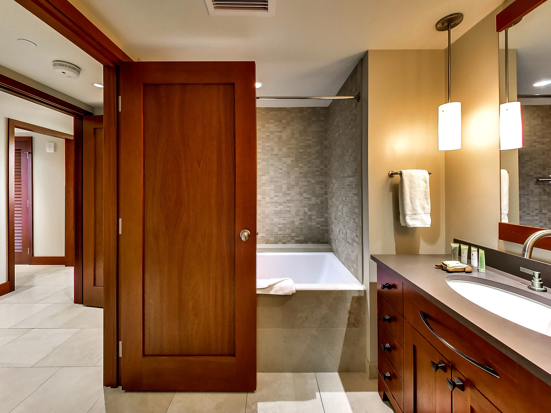 A bathroom with a bathtub, vanity, and wooden door.