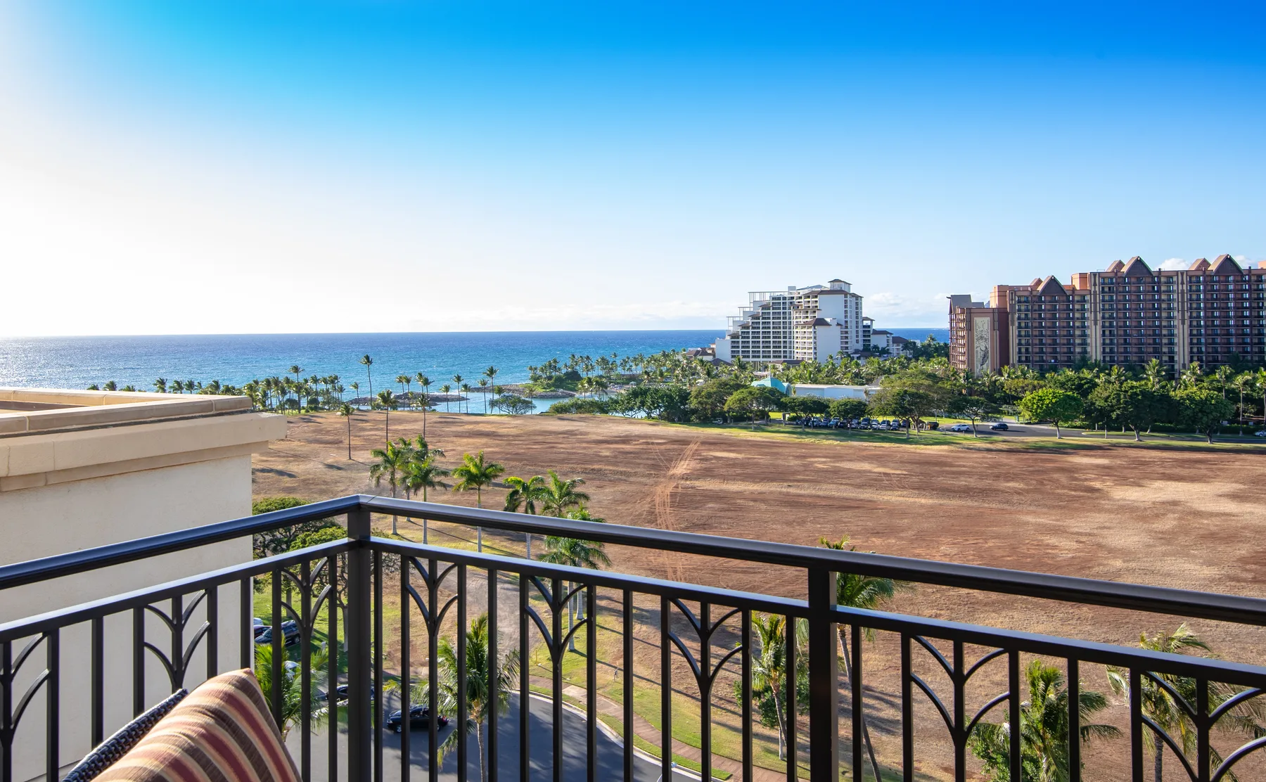 A balcony overlooks a landscaped area, coastal buildings, and the ocean.