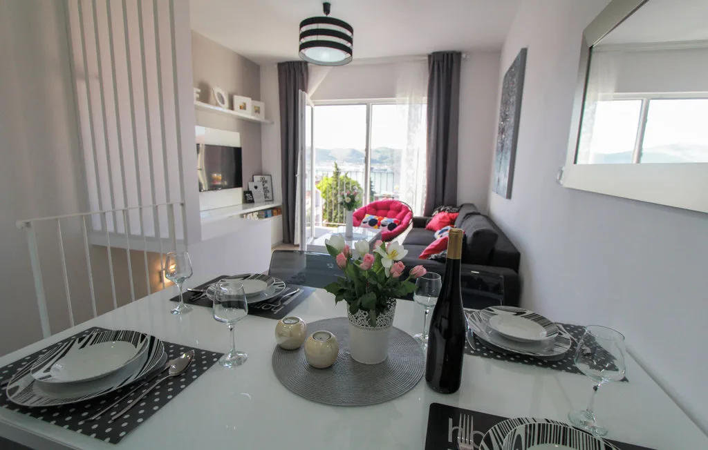 Una sala de estar y comedor con la mesa puesta y asientos junto a grandes ventanas.