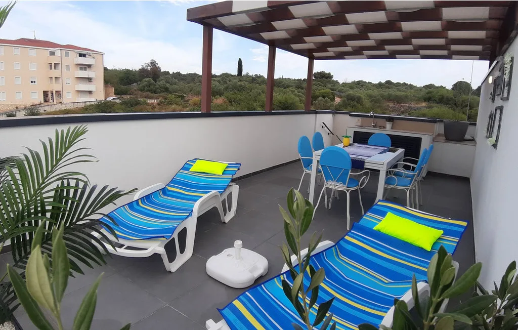 Una terraza en la azotea con tumbonas a rayas y una mesa de comedor al aire libre.