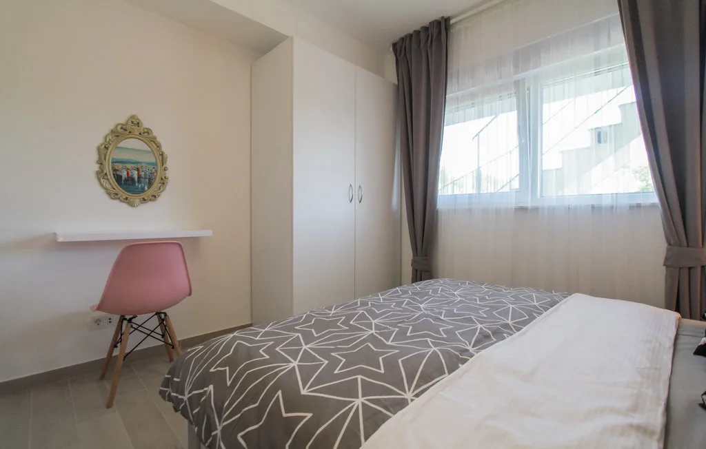 Un dormitorio con cama, armario y una gran ventana con cortinas.