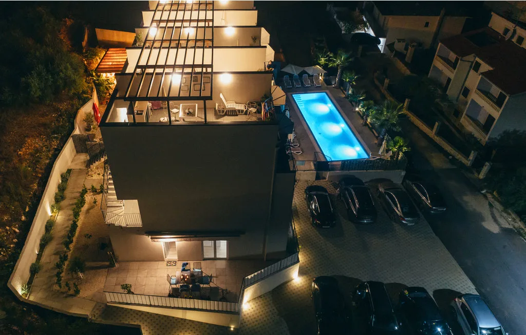 Se ven un edificio moderno y una piscina exterior iluminada de noche.