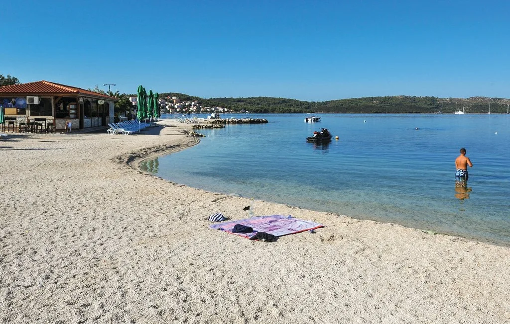 Una playa de arena junto a aguas tranquilas, con un café frente a la costa.