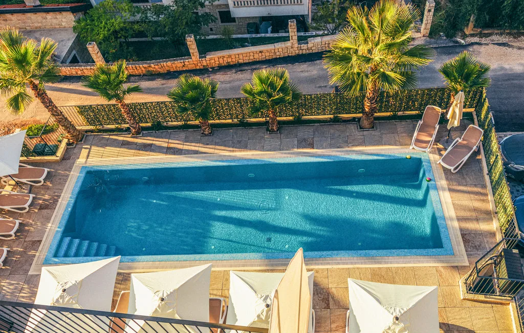 Una piscina al aire libre rodeada de una terraza pavimentada y tumbonas.