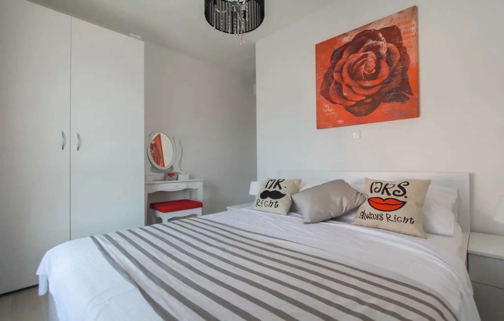 Un dormitorio con una colcha a rayas y un cuadro de una rosa roja sobre la cama.