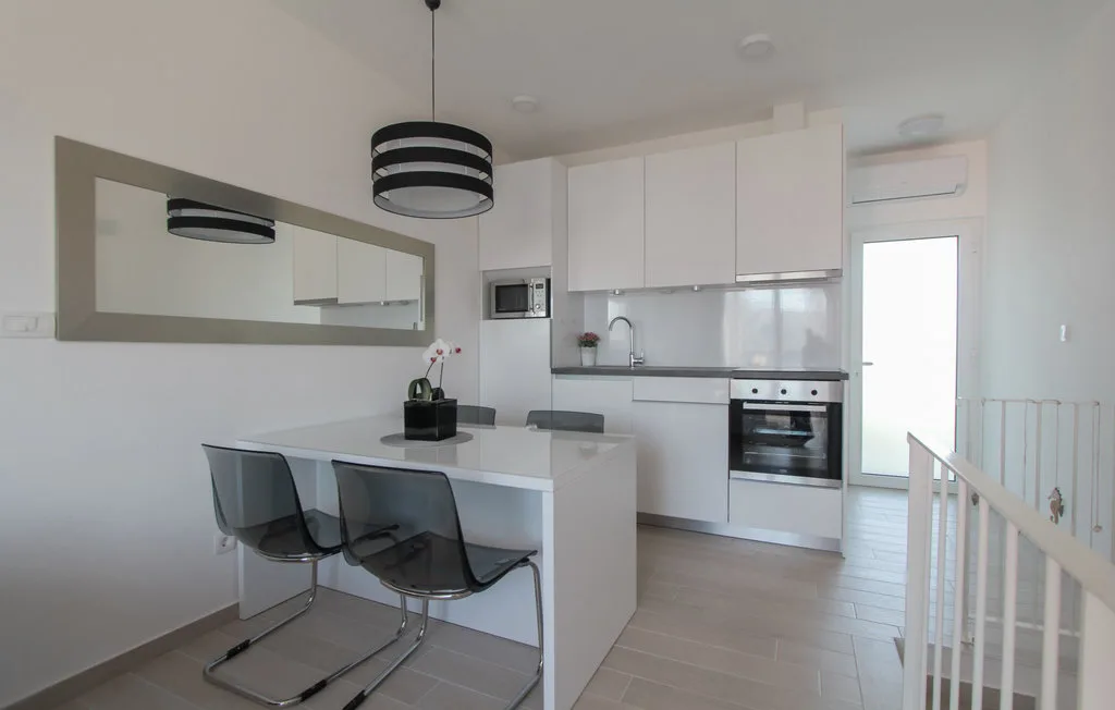 Una cocina luminosa con una barra, asientos y armarios blancos.