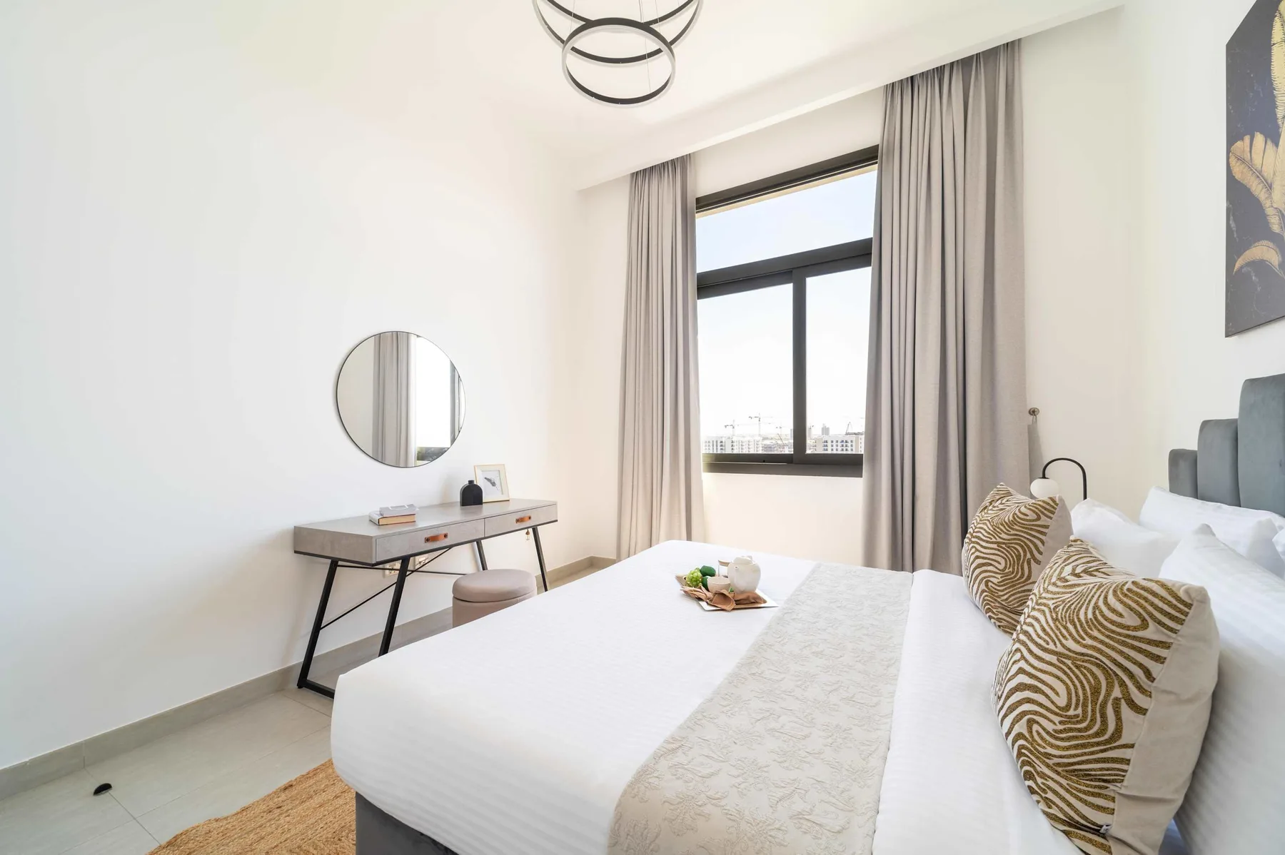 Un dormitorio luminoso con una cama, un escritorio y una ventana grande.
