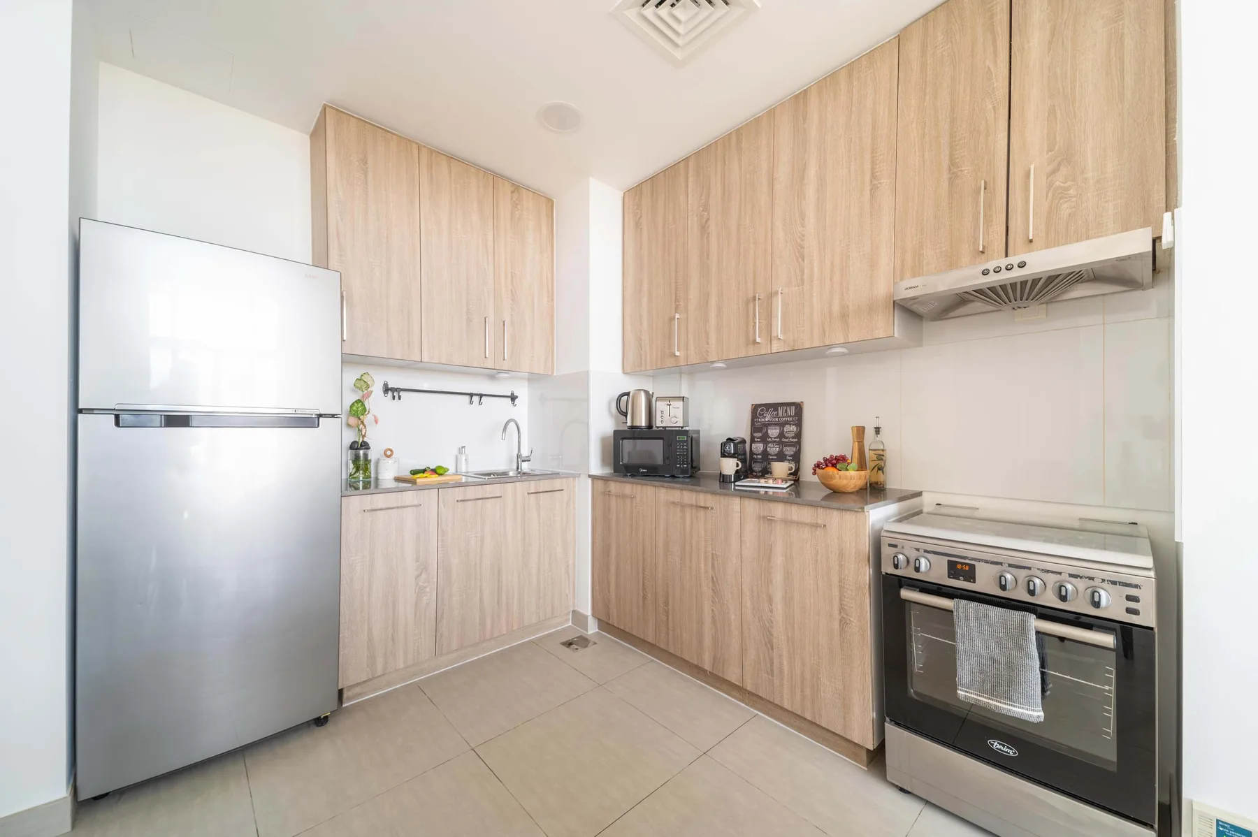 Una cocina luminosa con gabinetes de madera, un refrigerador y una estufa.