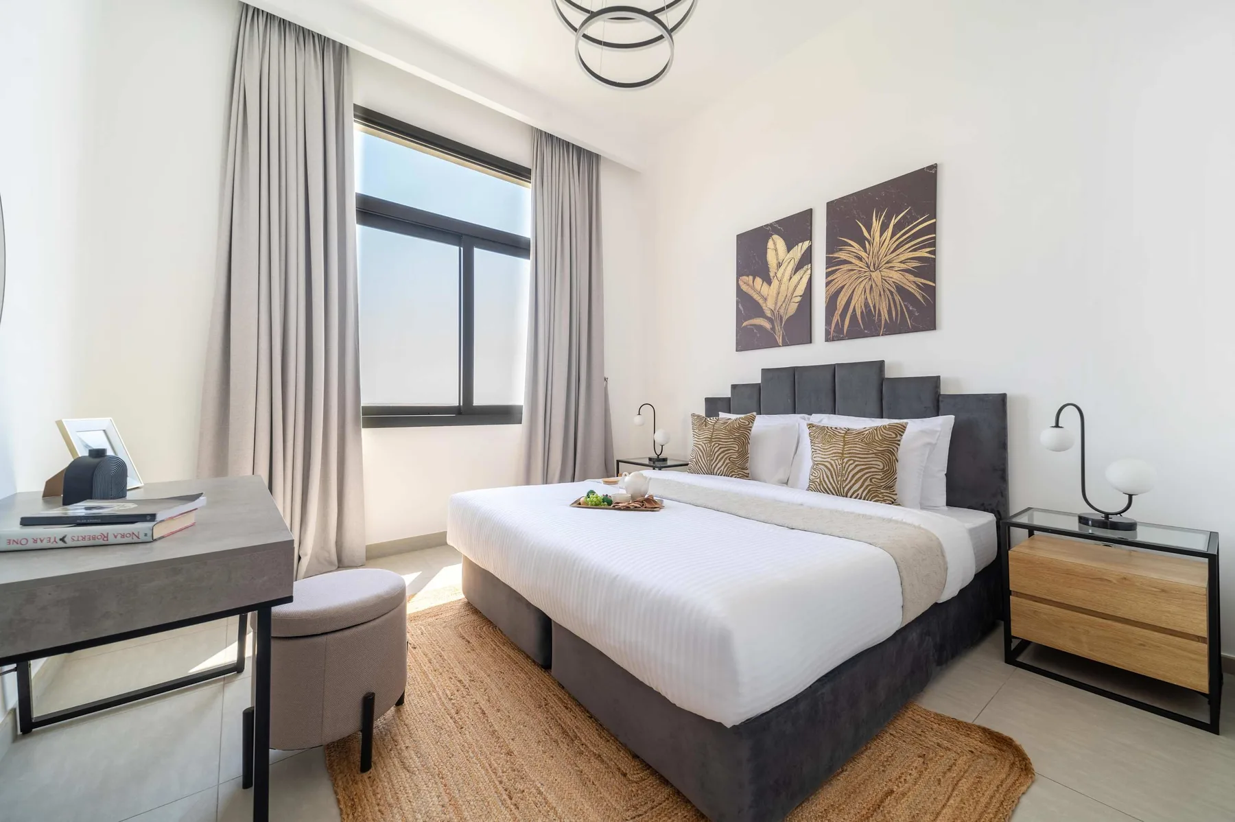 Un dormitorio luminoso con una cama bien tendida y una ventana grande.