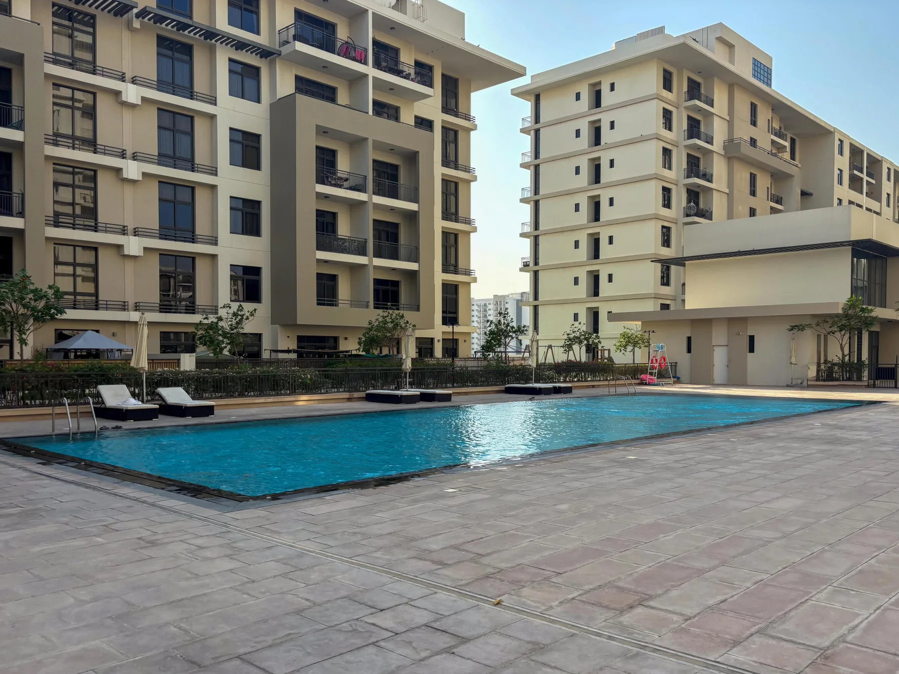 Una piscina al aire libre está junto a varios edificios de apartamentos modernos.