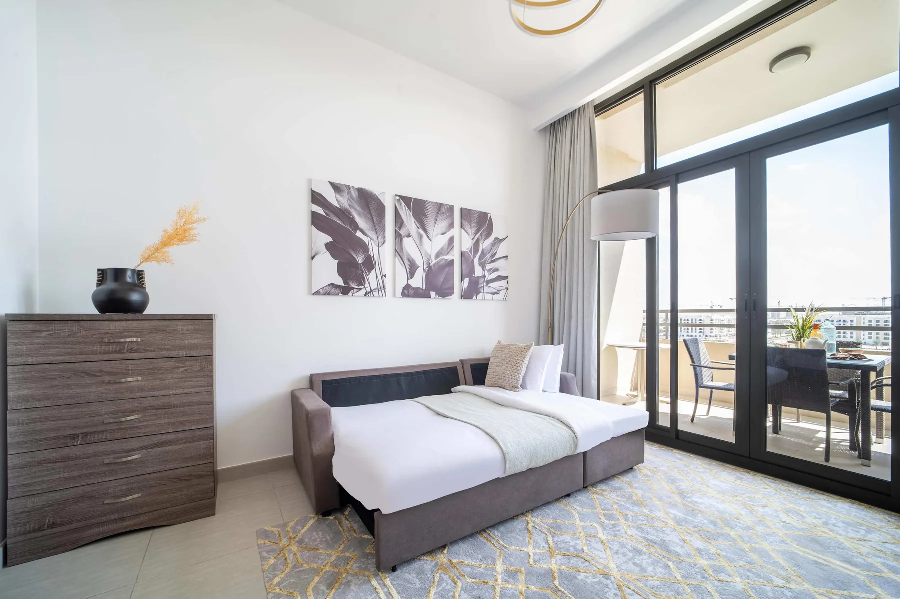 Un dormitorio luminoso con una cama junto a grandes puertas de vidrio que dan a un balcón.