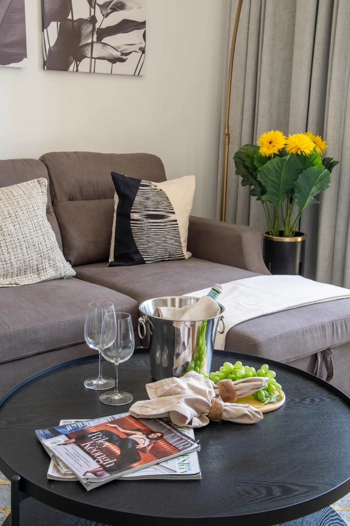 A living room seating area with a round coffee table and flowers beside the sofa.