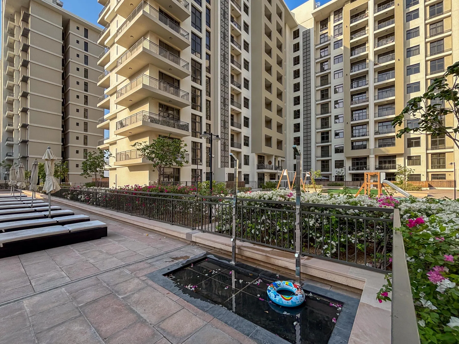 Un patio ajardinado de apartamentos con un estanque poco profundo y juegos infantiles.