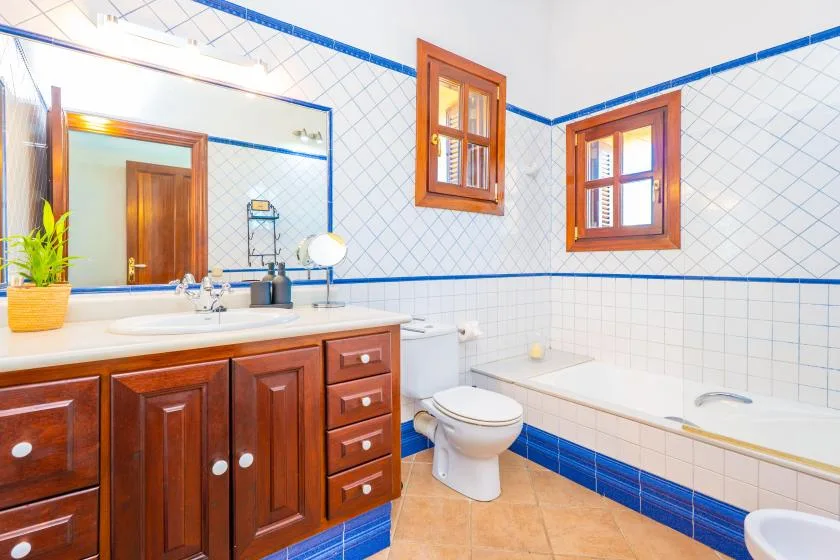 A tiled bathroom with a wooden vanity, toilet, and bathtub.