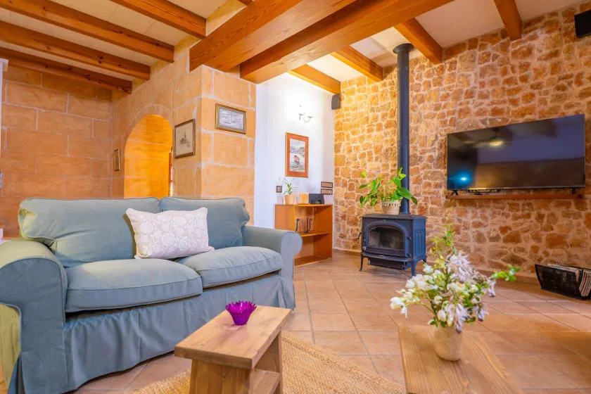 A living room with blue seating, exposed wooden beams, and a television.