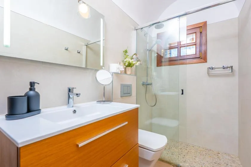 A bright bathroom with a vanity, toilet, and glass shower.