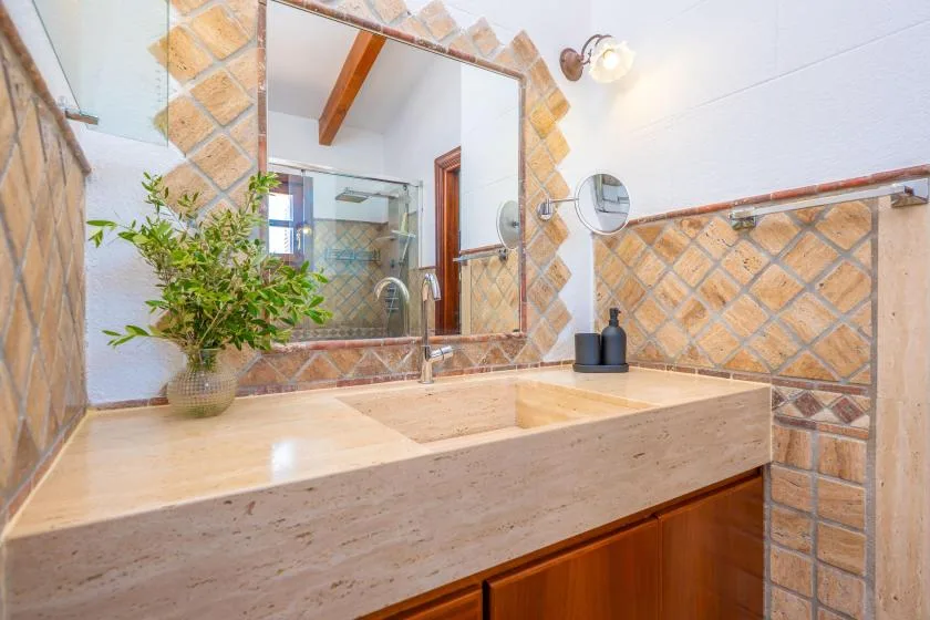 A tiled bathroom vanity with a large mirror and sink.