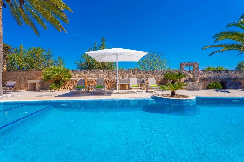 An outdoor swimming pool with a white umbrella and lounge seating.
