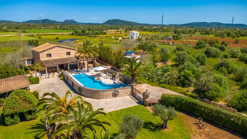 A countryside property with a swimming pool, garden, and open fields beyond.