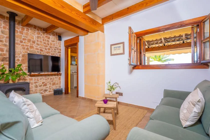A living room with seating, a television, and exposed wooden ceiling beams.