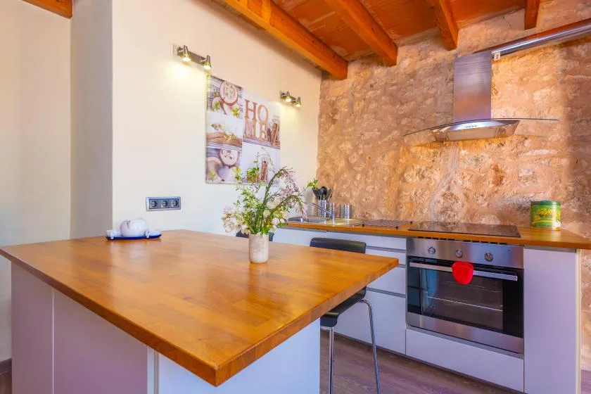 A rustic kitchen with a wooden island, exposed beams, and a built-in oven.