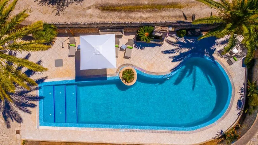An outdoor swimming pool with a curved edge and a shaded seating area.