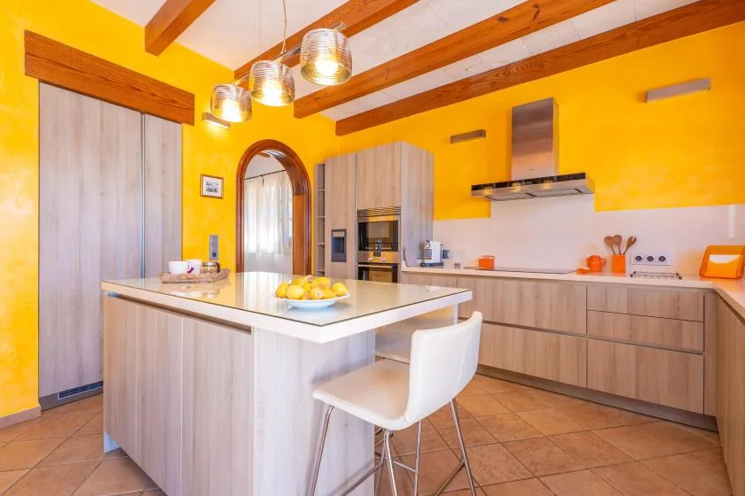 A bright kitchen with a central island and wooden cabinets.