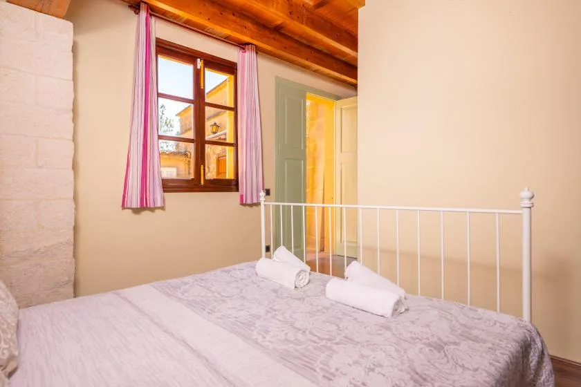 A bedroom with a bed, a window, and pink curtains.