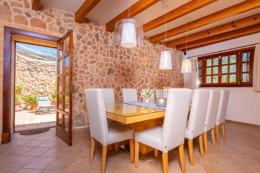 A dining room with a wooden table, upholstered seating, and exposed ceiling beams.