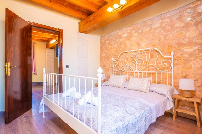 A bedroom with a white metal bed and exposed wooden ceiling beams.