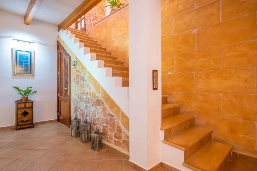 An interior hallway with a staircase beside a stone accent wall.