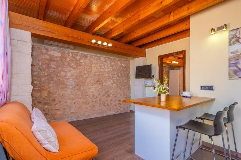 A living area with orange seating, a stone wall, and a wooden ceiling.
